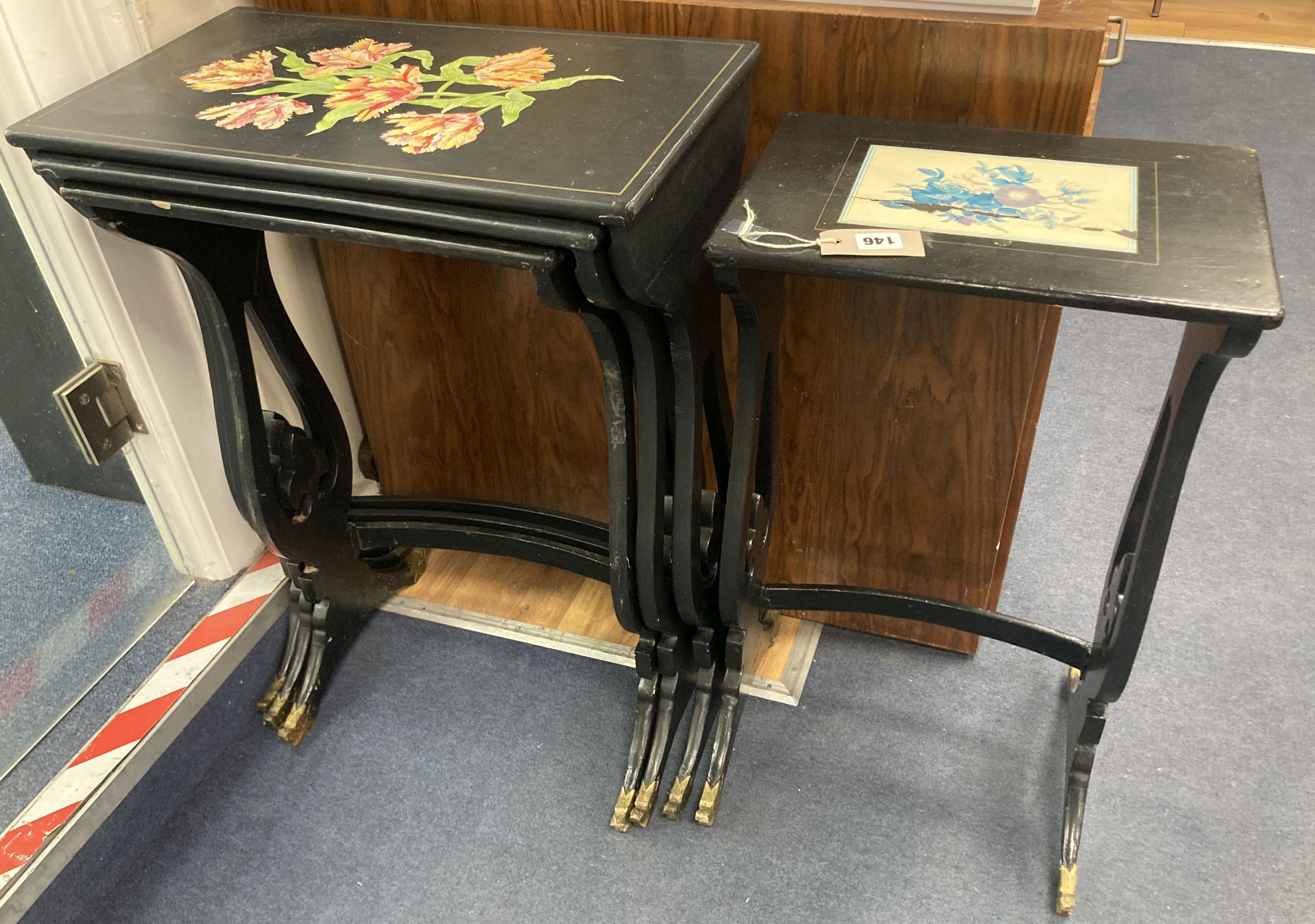 A graduating nest of four Regency style occasional tables with lyre shaped supports, black painted finish with gilt mask detail to supp